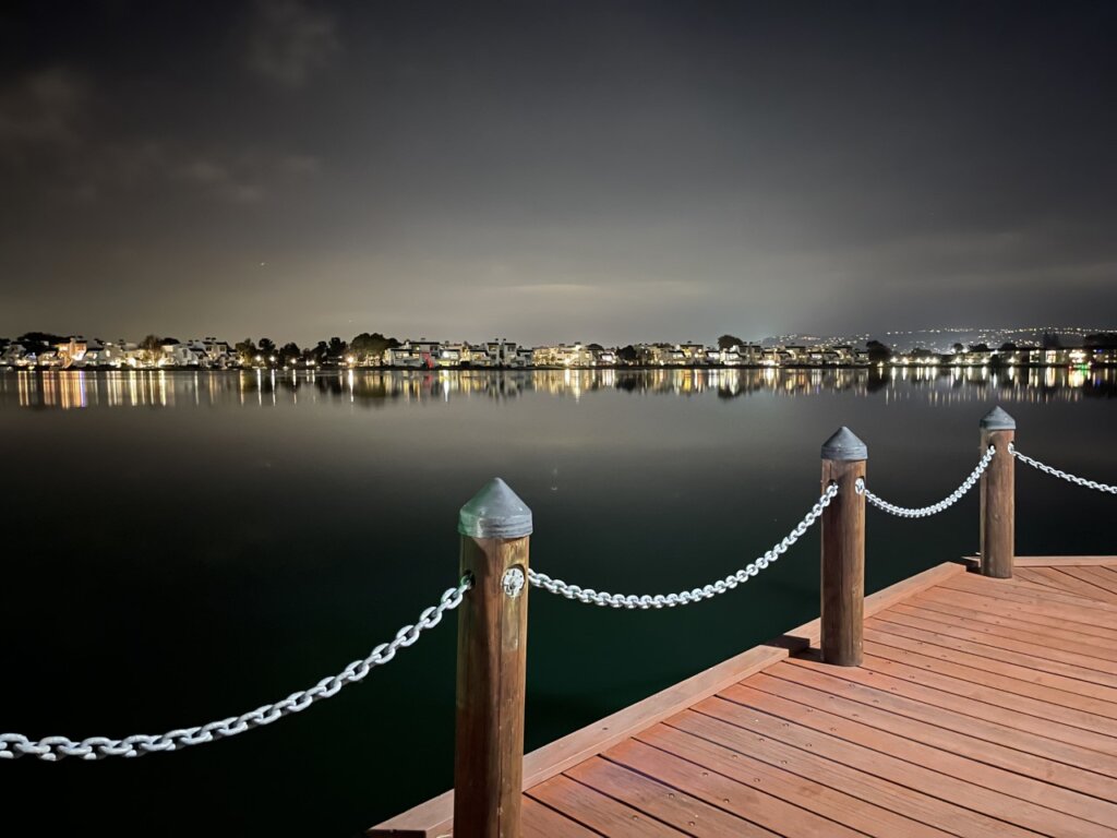 Wooden walkway in front of a body of water at night time at Ryan Park in Foster City