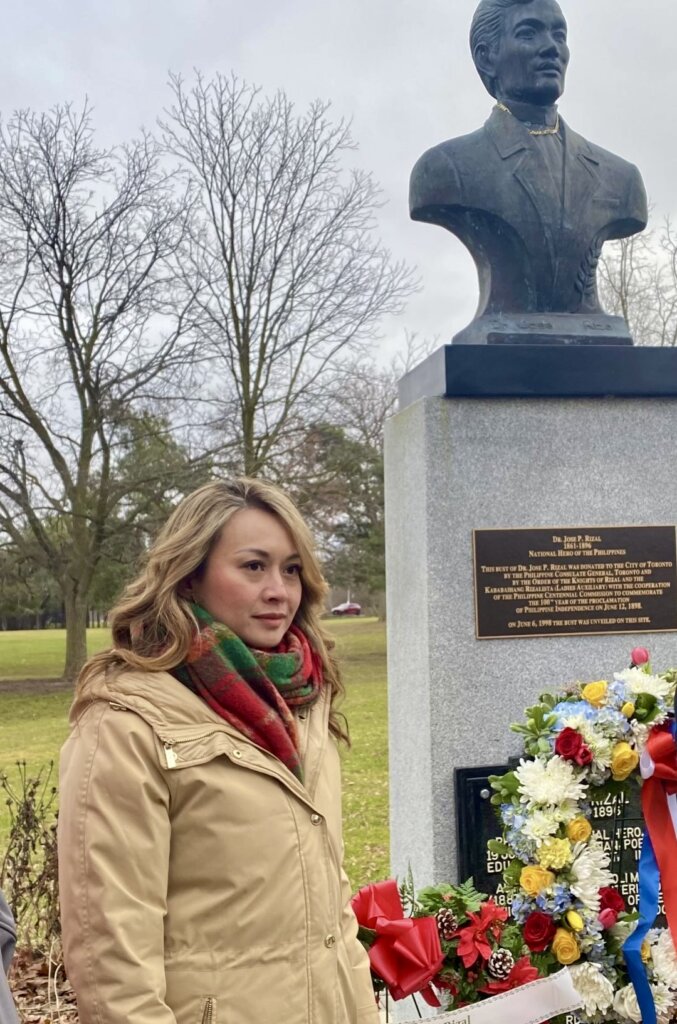 Minister of Small Business Rechie Valdez standing close to a bronze bust of Philippine hero Dr. Jose P. Rizal.