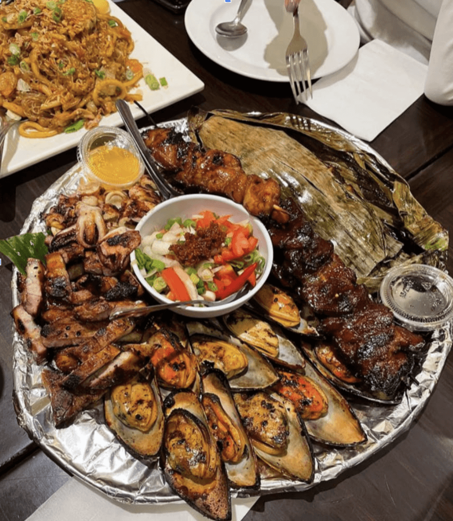 A round aluminum-wrapped platter with grilled meat, seafood and vegetables.