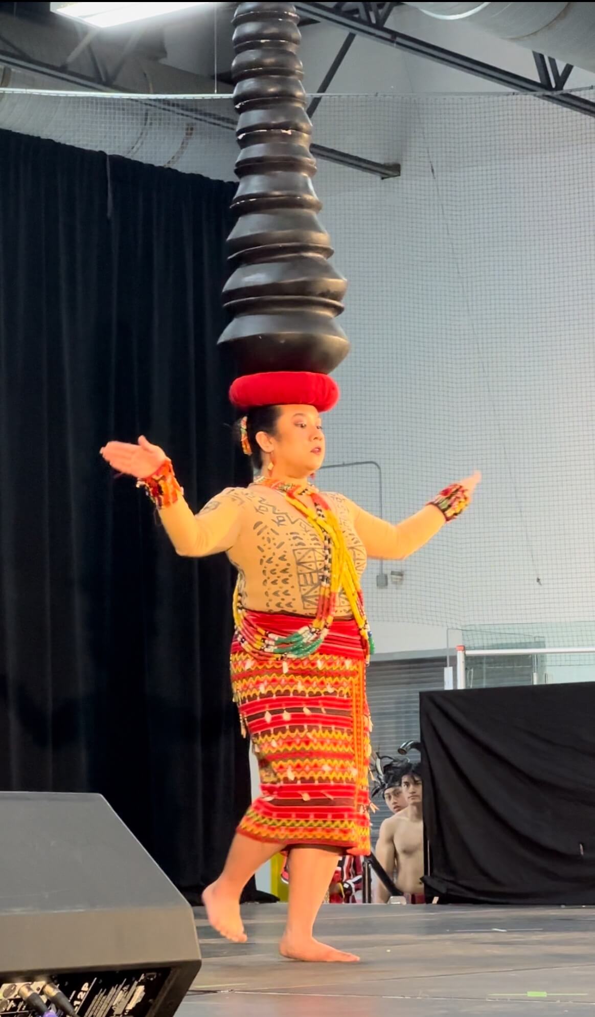 A woman dances with ten clay pots balanced on her head.